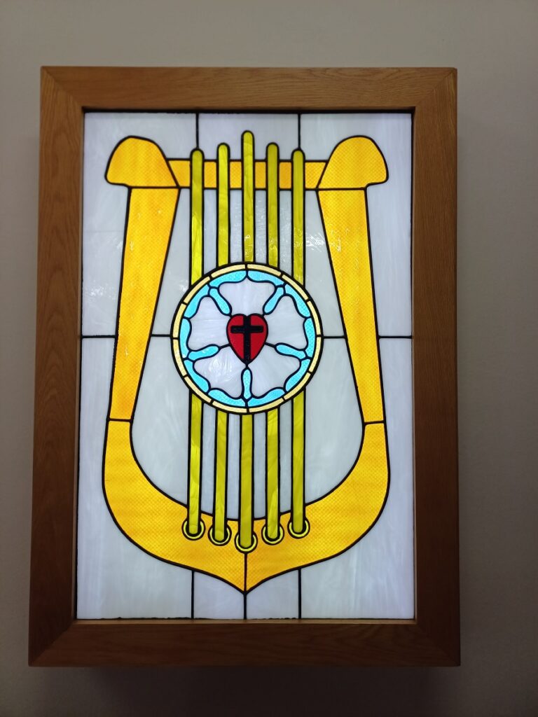 A "stained glass" lightbox of a harp with Luther's Rose in the centre