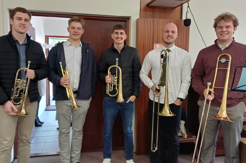 Five smiling young men holding brass instruments